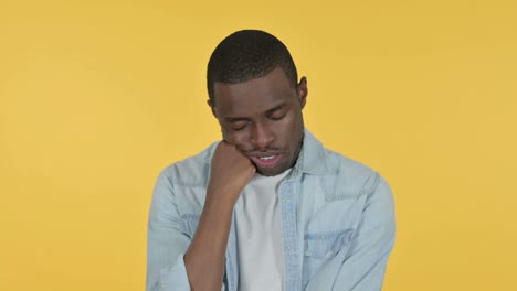 sleepy young african man taking nap, yellow background