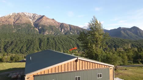 rotating view of an airplane hanger with a windsock on the top.  near palmer, alasaka with mountains in the backdrop.