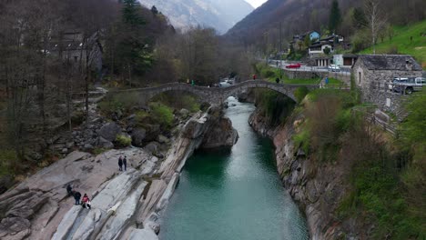 aerial shot over a turquoise river and an old and picturesque bridge in val verzasca in switzerland