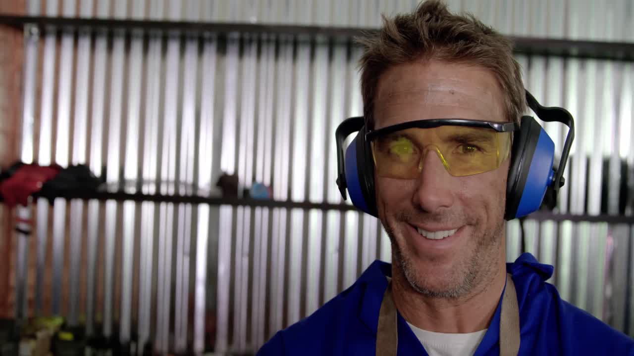 mecánico masculino mirando a la cámara en el garaje de reparación 4k