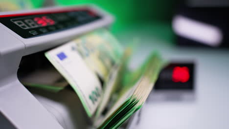 euro banknotes rotated and counted in cash counting machine. number run quickly up at the display. close up. blurred backdrop.