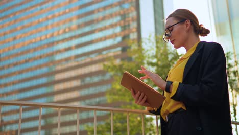 attractive businesswoman in eyeglasses using ipad tablet against