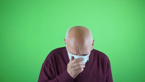 un anciano enfermo con una máscara estornuda la cabeza aislada en chromakey