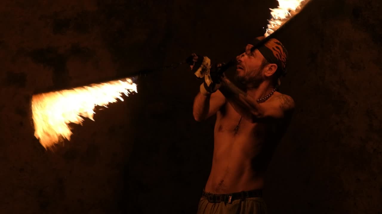 Slow motion shot of a man performing with a fire whip