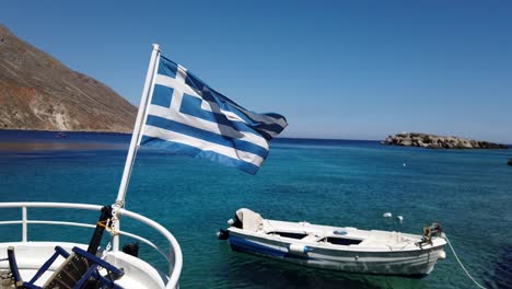 greek flag fluttering in the air in slow motion in the middle of the sea and a cloudless blue sky