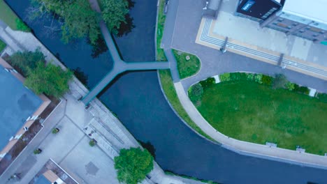 aerial drone footage rotation from above looking down at the little ouse river with footbridge in the historical town of thetford in norfolk, england