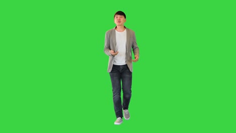 young asian man walks telling something on a green screen, chroma key