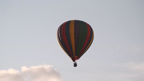 slomo tracking shot of colorful hot air balloon floating away in blue sky