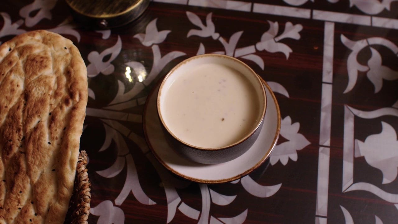 Deliziosa zuppa cremosa e pane fresco su un tavolo decorato, tipica della cucina mediorientale.