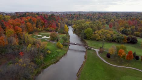 Fly-over-a-river-in-a-park-in-a-fall,-cloudy,-moody-day