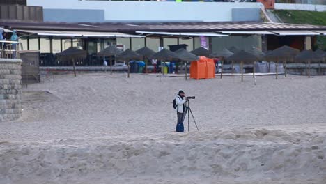 photographer captures a stunning landscape photo on the beach during a colourful twilight sky, while speaking on the phone