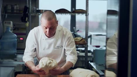 the baker kneads the wet bread dough