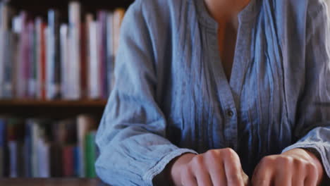 estudiante asiática con un hijab azul sentada y leyendo un libro de braille con los ojos cerrados