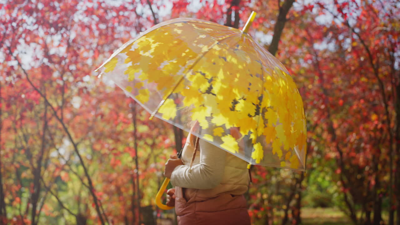 Bambina felice con un ombrello in un parco autunnale colorato
