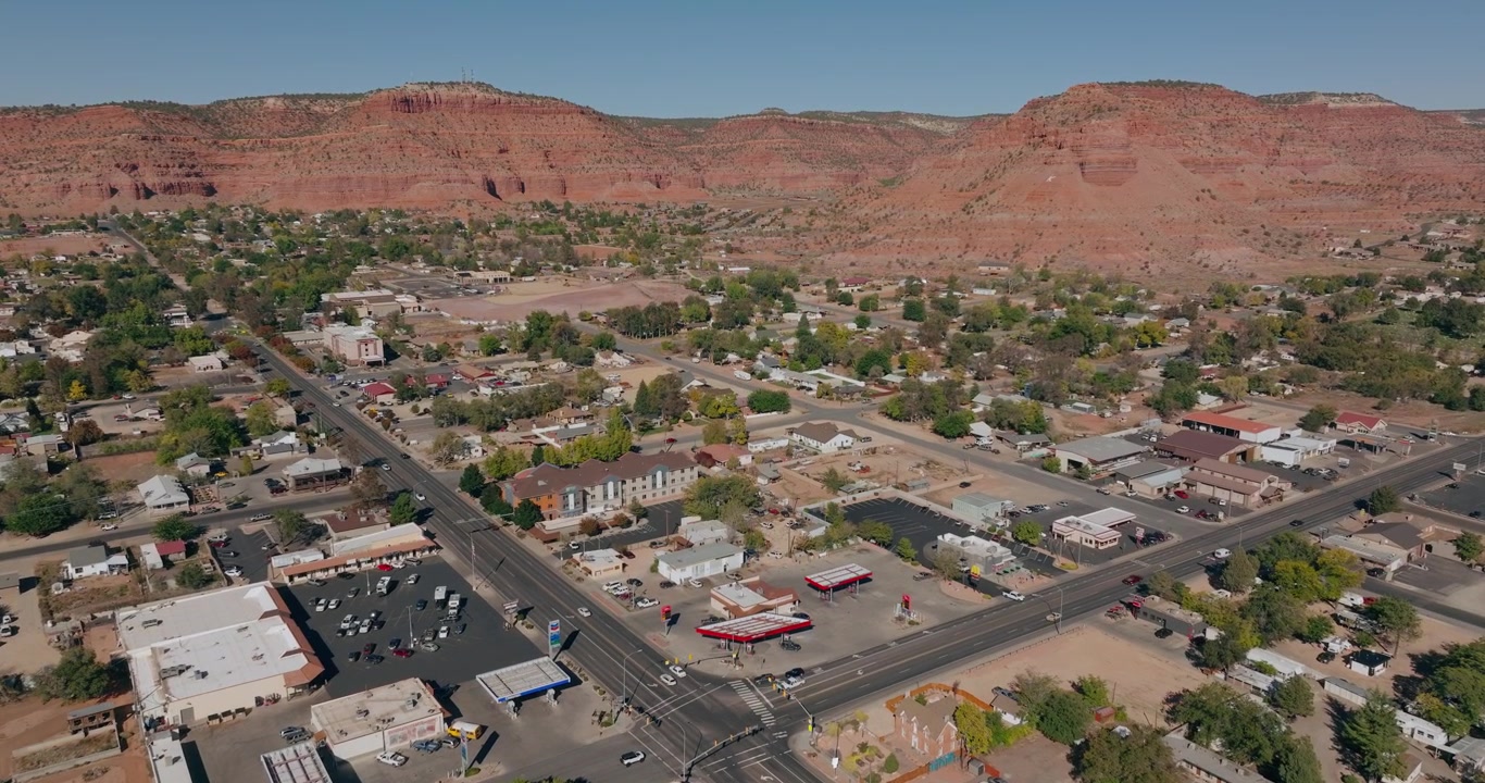 Ripresa aerea introduttiva con drone di strade e case del quartiere di Kanab, Utah, sotto imponenti mesas rosse del deserto