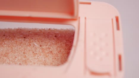 Raw-whole-dried-pink-himalayan-salt-in-a-container-on-white-,