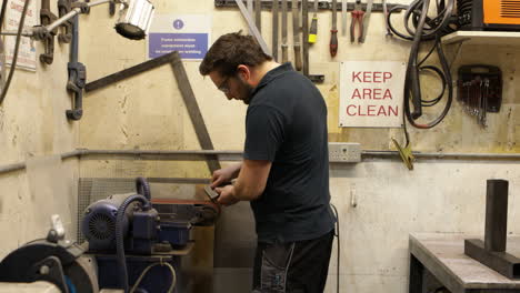 engineer working on linishers belt grinders in a tidy workshop with a keep area clean sign