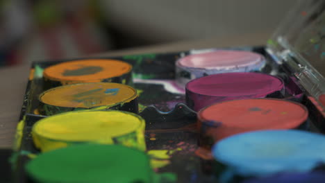 mediano de cerca de la mano de un niño cargando acuarela de un juego de pintura