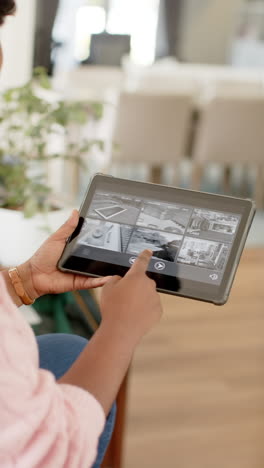 Vertical video of african american woman using tablet at home, slow motion