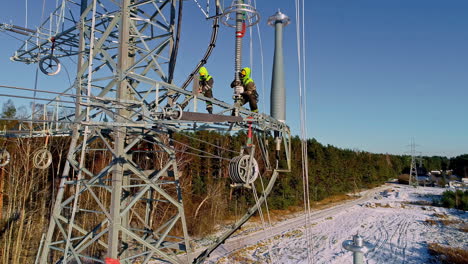 aerial drone shot of electrical workers installing electric poles along rural landscape on a sunny day during winter time