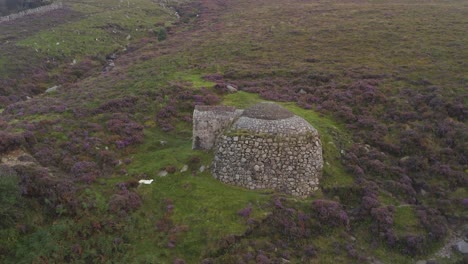 drone pulls back to showcase heathland of slieve donard with ice house centered