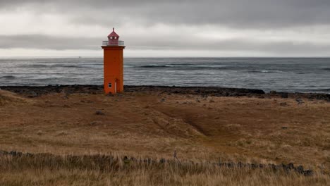 orange lighthouse on a rocky coastline