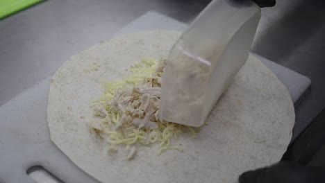 chef preparing chicken wrap in restaurant kitchen