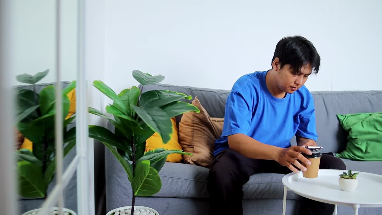 Young man relaxing on couch with coffee and phone modern home lifestyle inspiration