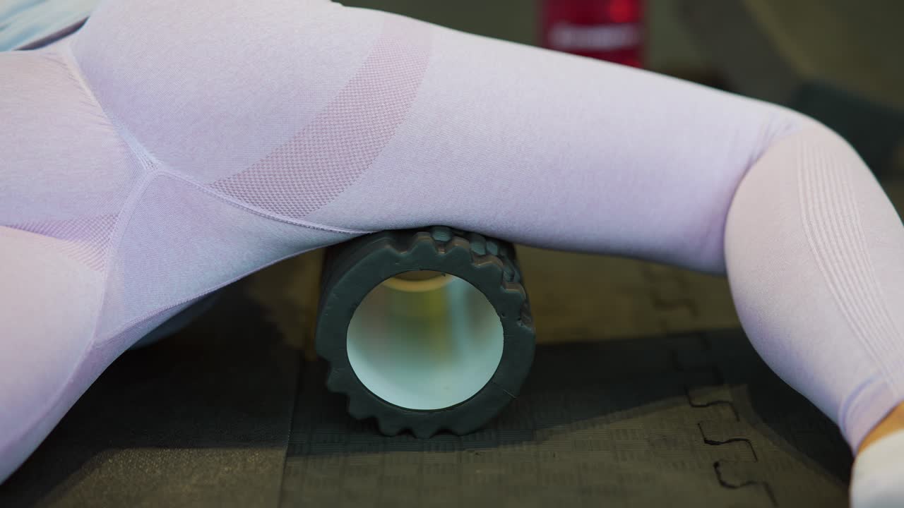 mujer usando un rodillo de espuma para estirar la cadera y las piernas