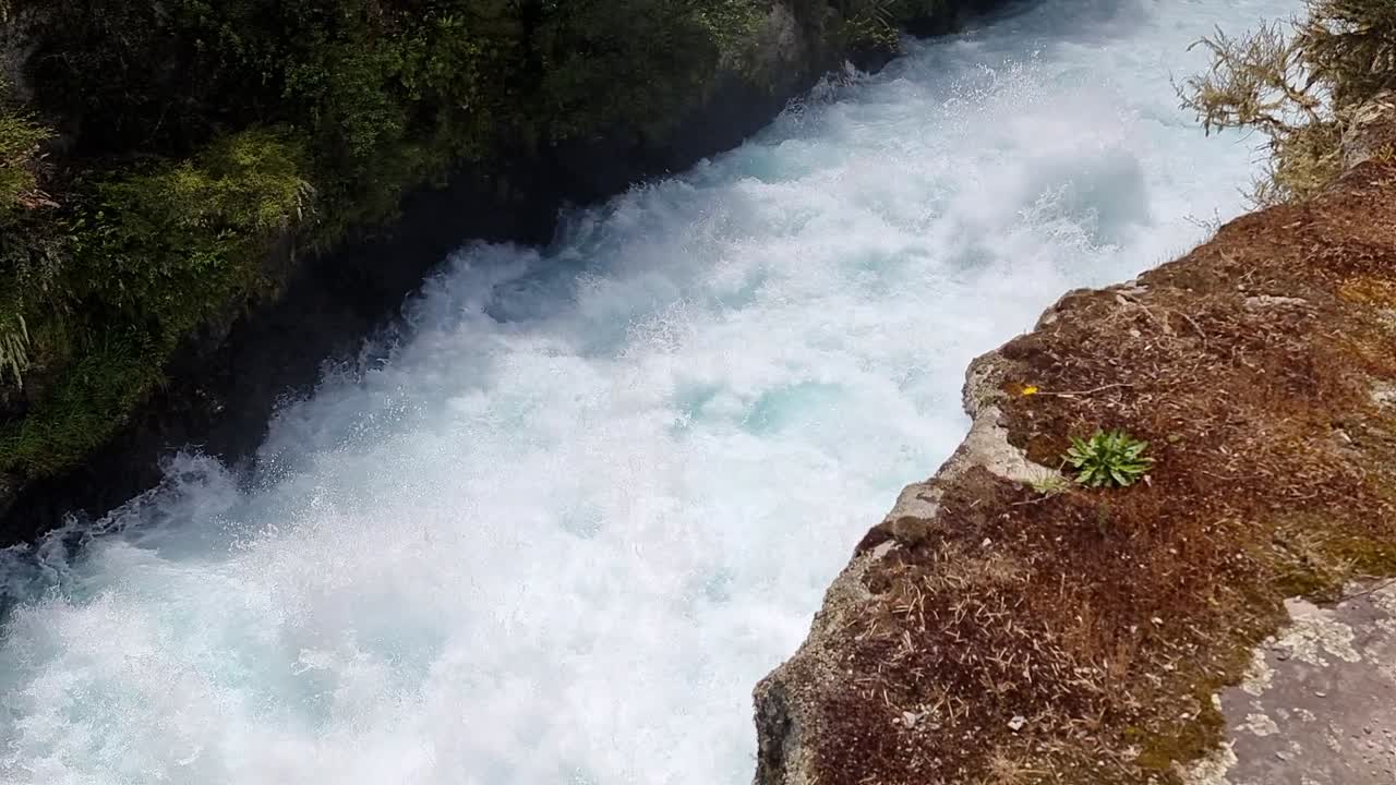 뉴질랜드의 후카 폭포 (huka falls) 의 협곡 안의 격동된 물을 내려다보고 있습니다.