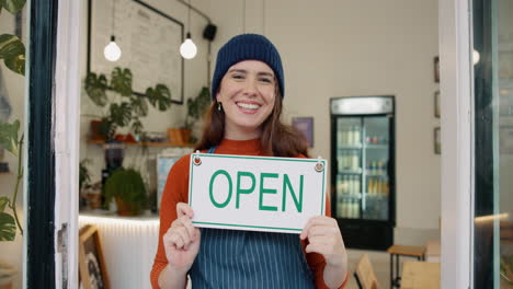 woman holding an open sign in her shop