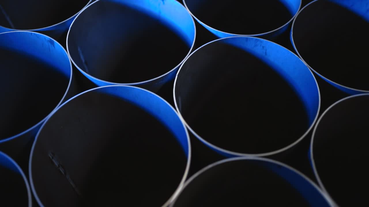 Overhead shot of round steel pipes stacked together with blue light
