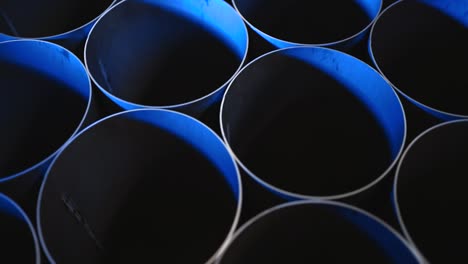 overhead shot of round steel pipes stacked together with blue light