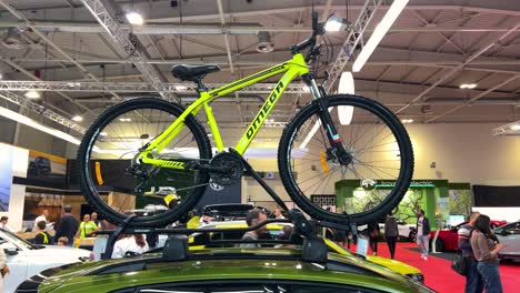 yellow mountain bike on car roof rack at a car show