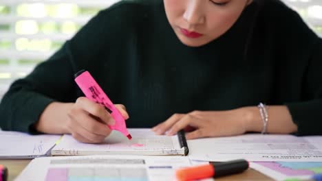 a focused student is reviewing notes and highlighting important sections in a notebook at a well-organized desk. natural light enhances the study environment.