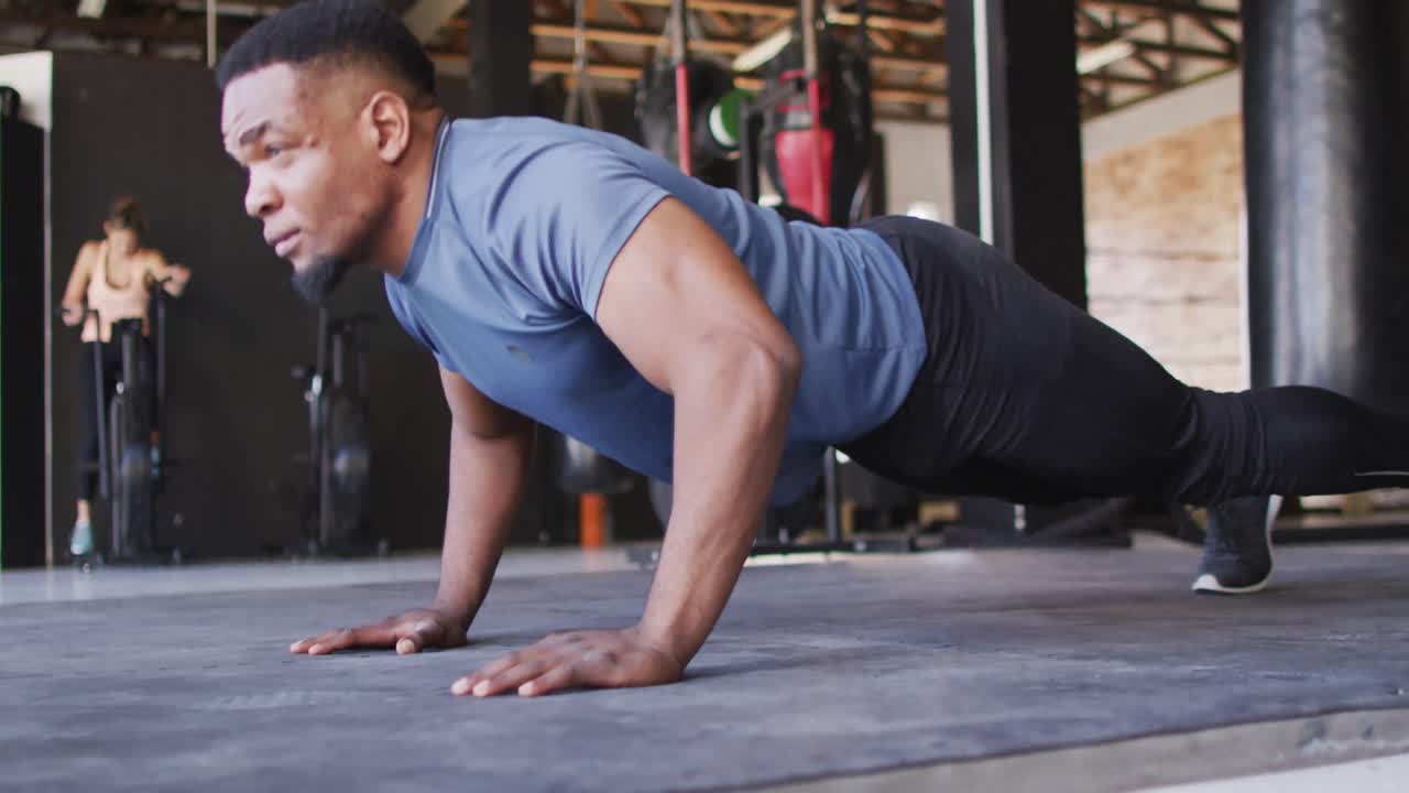video de un hombre en forma afroamericano haciendo flexiones en el gimnasio