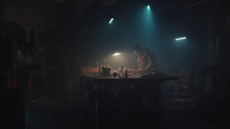 a bombmaker assembles a bomb in his workshop at night