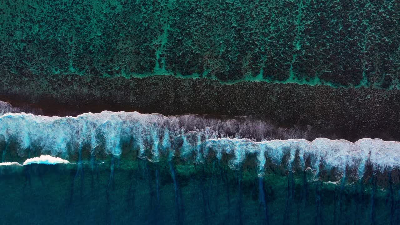 Vue aérienne de vagues océaniques turquoises s'écrasant sur un récif corallien.