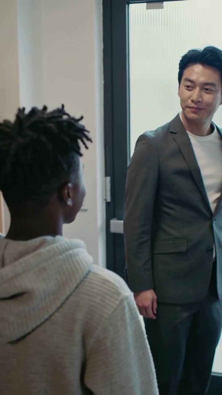 Vertical video: Walking teen in light hoodie seeing staff smile, stopping in library by bookshelves