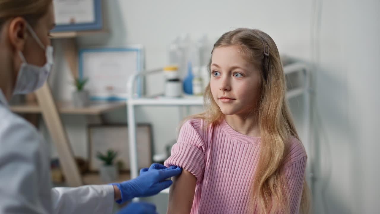 Doctor giving child injection in medical facility closeup. Cute girl visiting