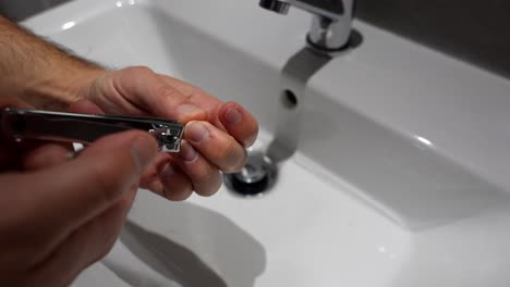 close-up of male hands clipping nails over bathroom sink. high angle, 4k