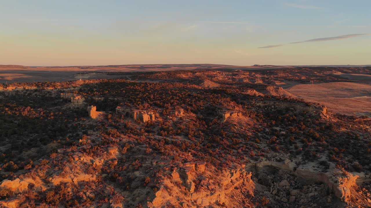 Uma vista aérea suave captura a primeira luz da manhã iluminando uma vasta mesa desértica. Esta paisagem em 4K apresenta o brilho quente e a atmosfera pacífica de uma natureza intocada do Sudoeste
