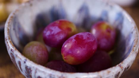 small bowl with red grapes being placed down, close-up shot