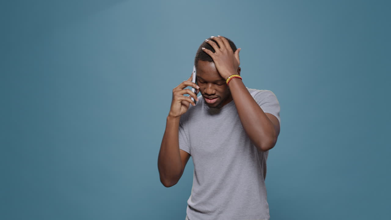 Millennial man talking on smartphone call over blue background