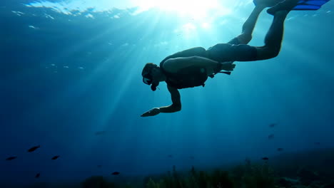 person snorkeling underwater with sun rays