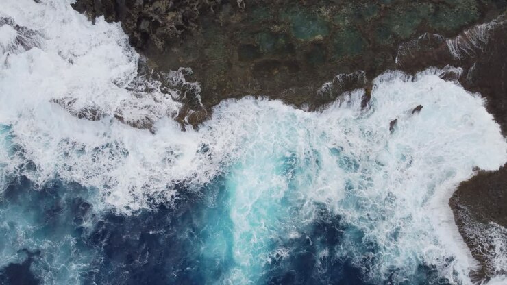 Bird's eye view of ocean waves crashing on rocks
