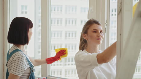 dos mujeres limpiando ventanas