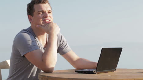 man typing on a small laptop computer