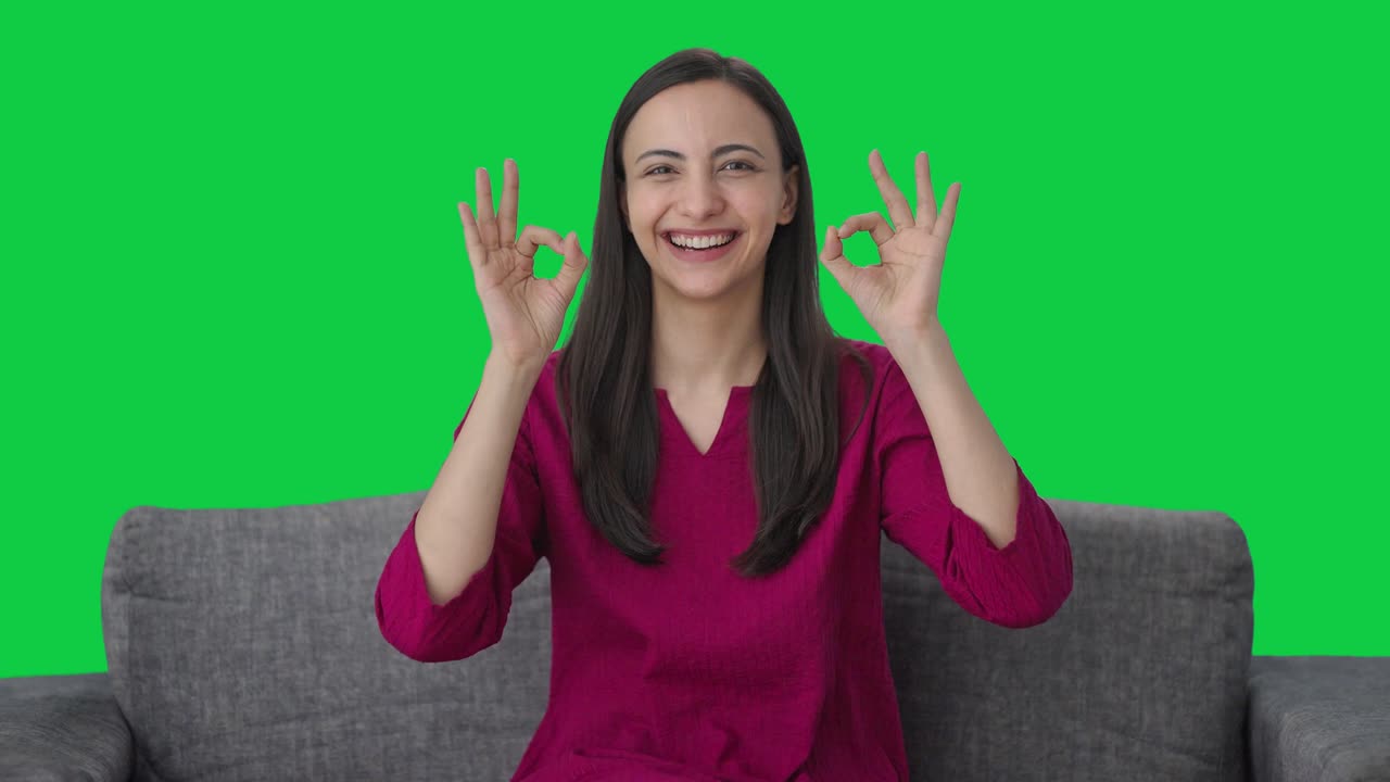Donna indiana felice che fa il segno 'ok' su sfondo Green screen