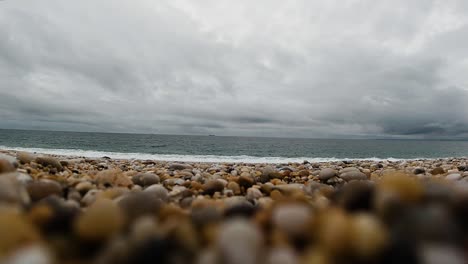 wide landscape view of beach with dark cloudscape and oil tanker in the distance in slow motion